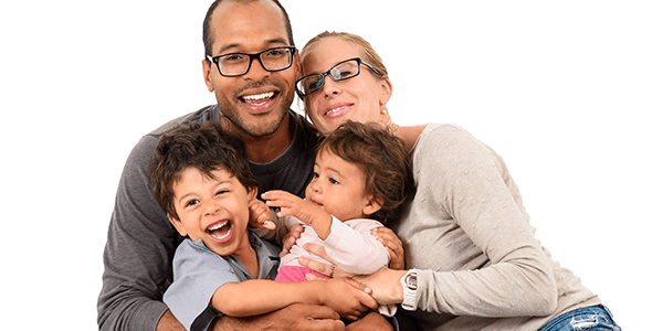 Husband and wife sitting on the floor holding their baby and toddler in their laps. 