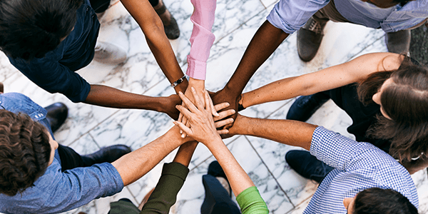 10 people in a circle with their hands stacked on top of each other. 