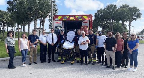 group of adults stand by ambulance with an empty stretcher